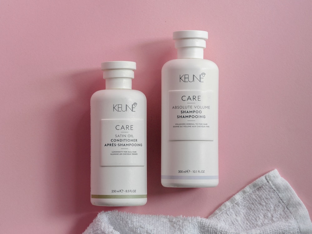 two bottles of keune hair care on a pink background