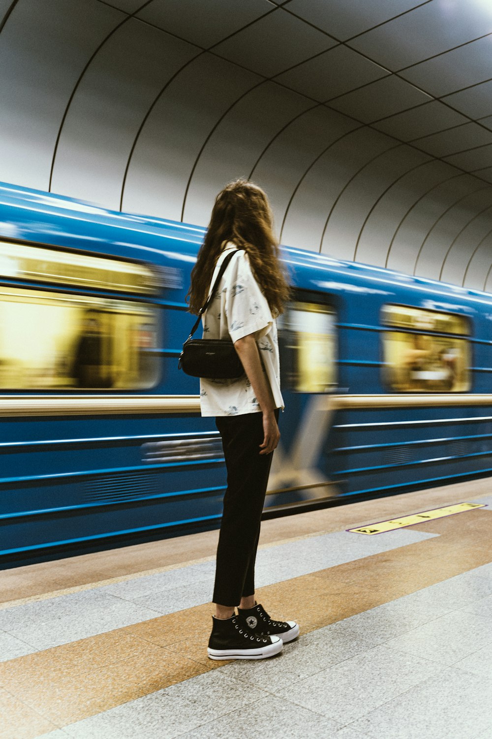 a woman standing on a platform waiting for a train