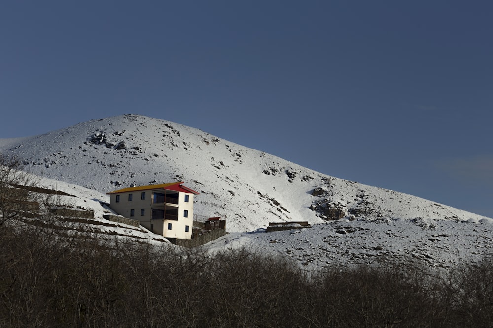 a house on a hill with a snow covered mountain in the background
