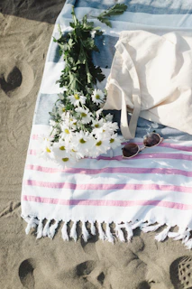 a towel, sunglasses, and flowers on the beach