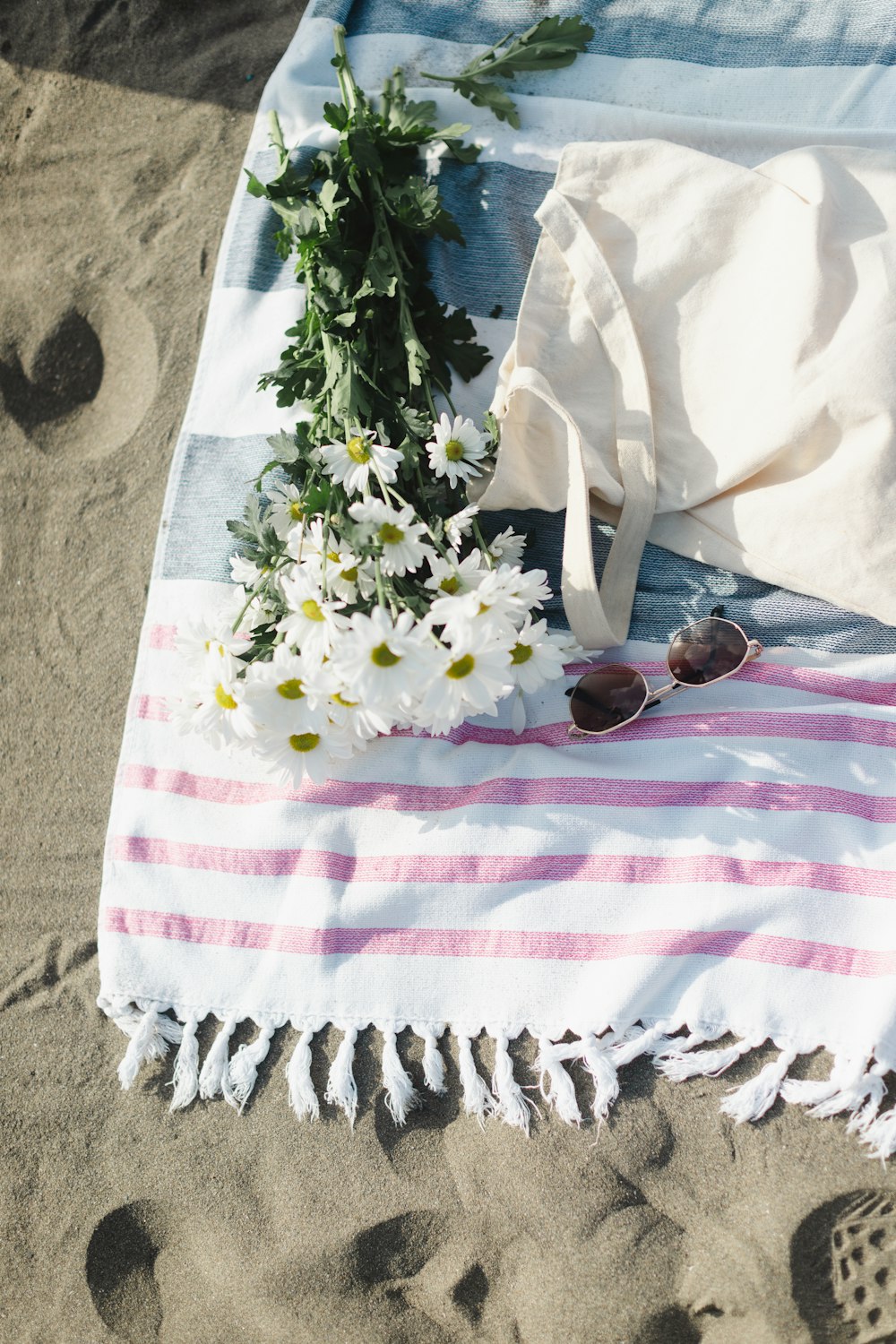 a towel, sunglasses, and flowers on the beach
