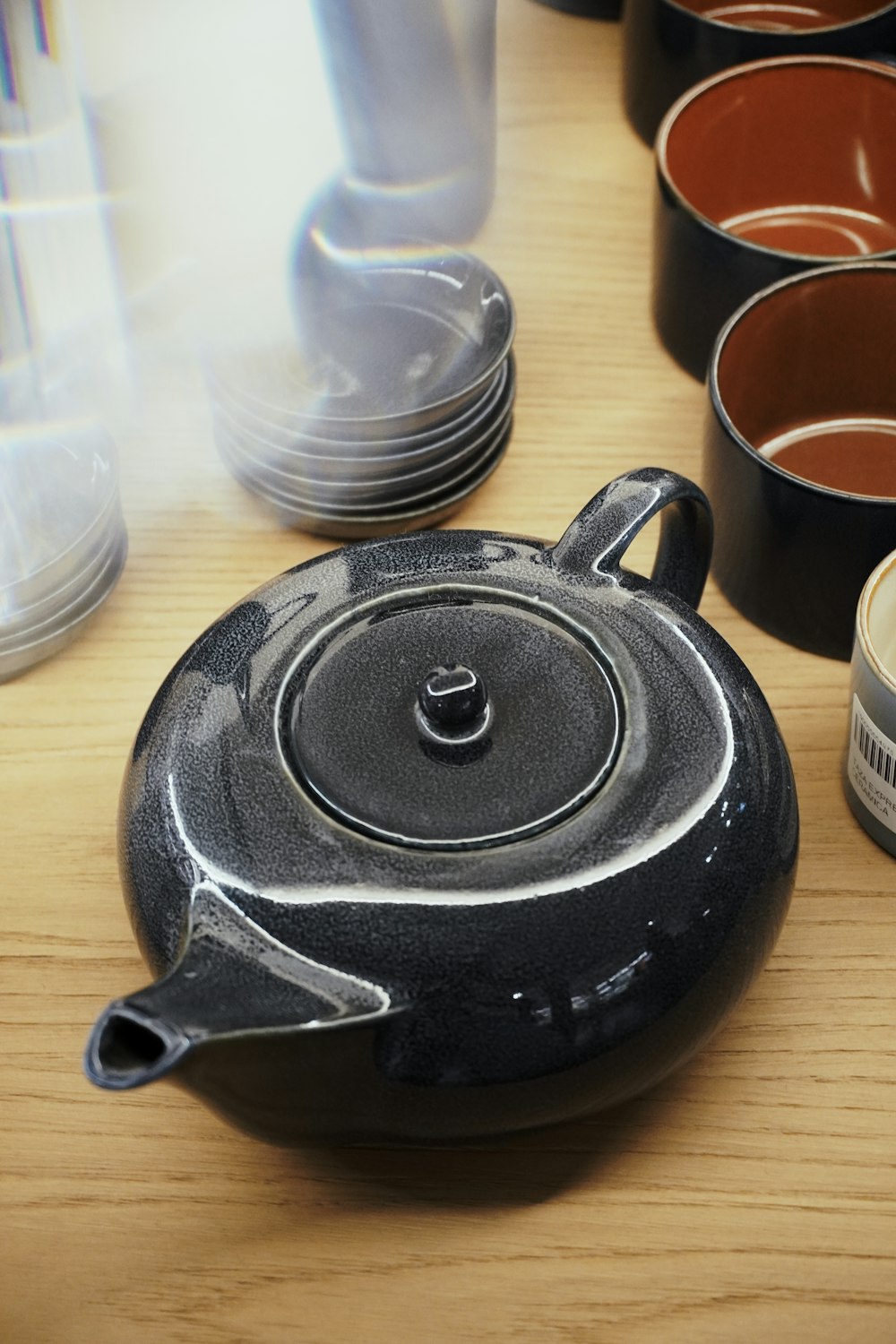 a black tea pot sitting on top of a wooden table