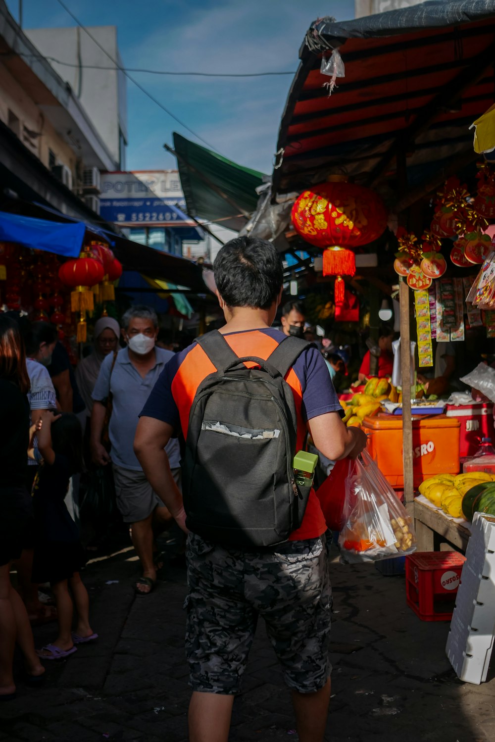 a man with a backpack is walking through a market