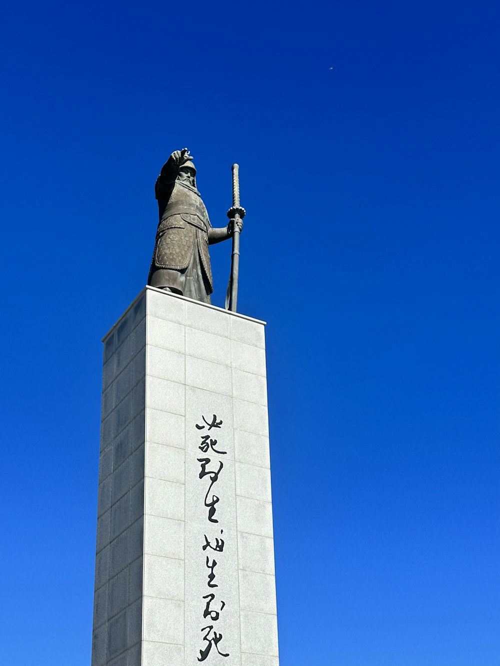 a statue of a man holding a sword in front of a blue sky
