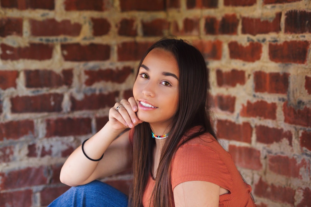 a woman sitting on a brick wall posing for a picture