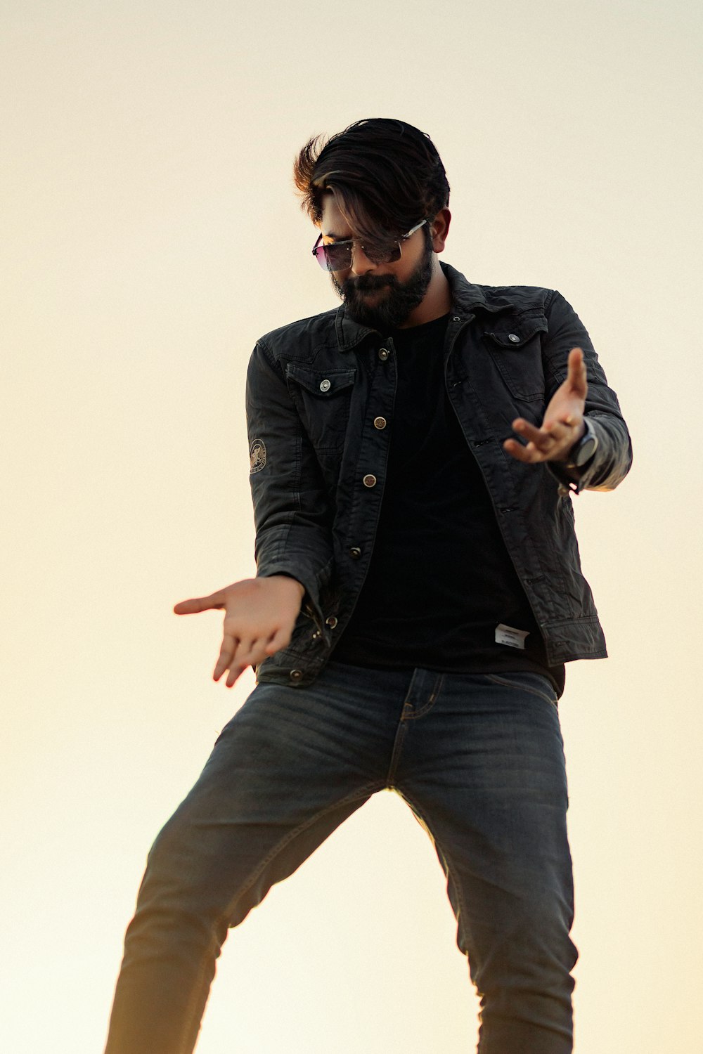 a man in a black shirt and jeans doing a trick on a skateboard