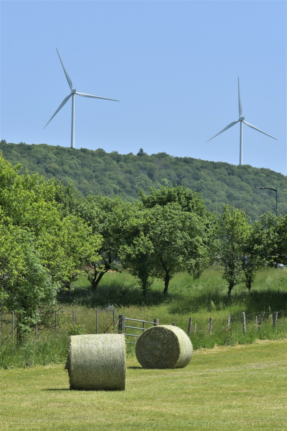 Due balle di fieno in un campo con turbine eoliche sullo sfondo