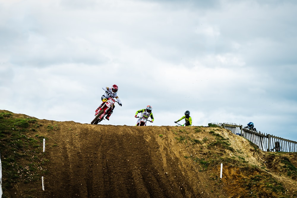 a group of people riding motorcycles on top of a dirt hill