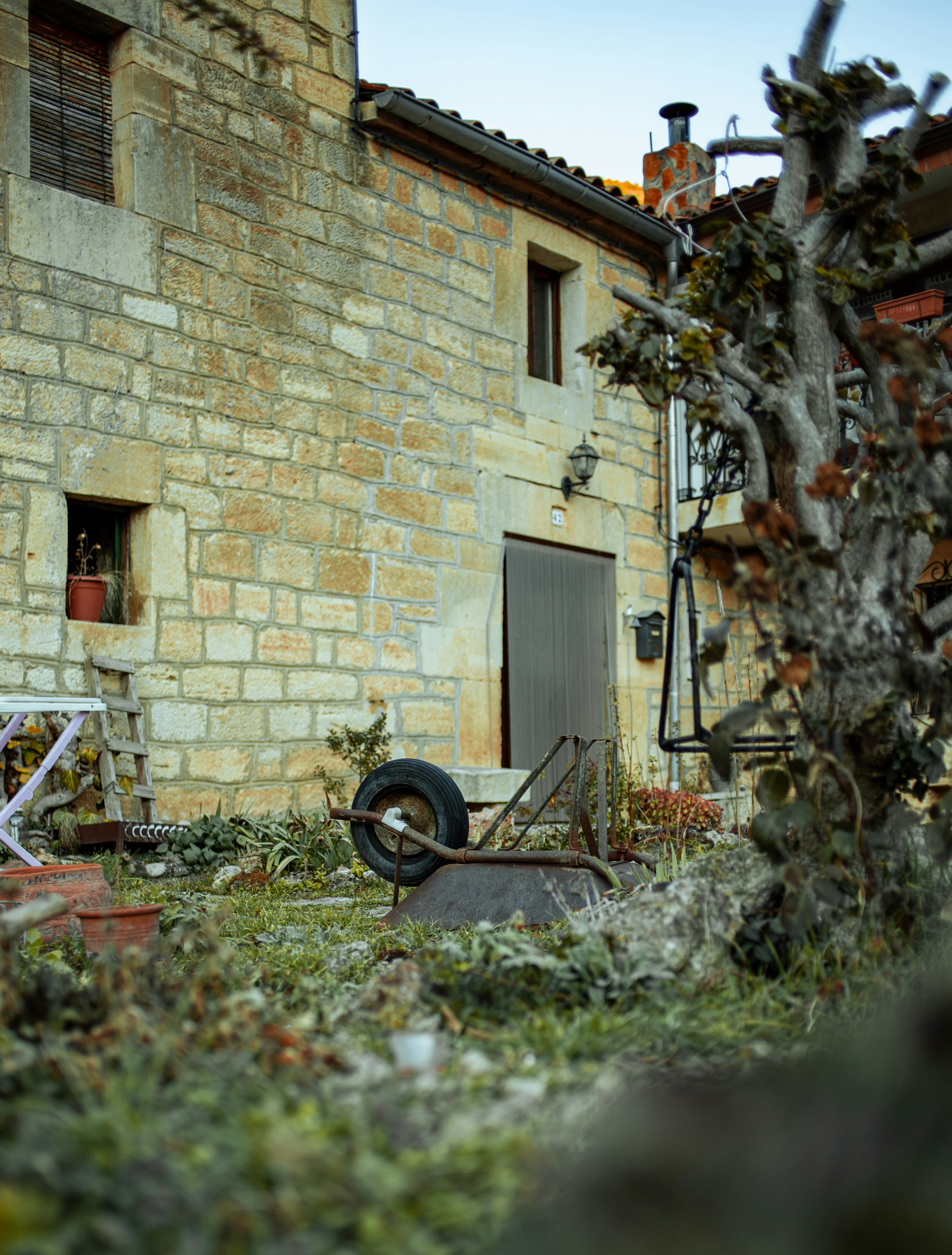 Un vecchio edificio con una ruota e una sedia di fronte ad esso