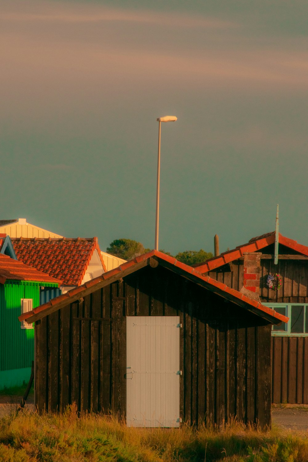 a building with a white door and a green building with a red roof