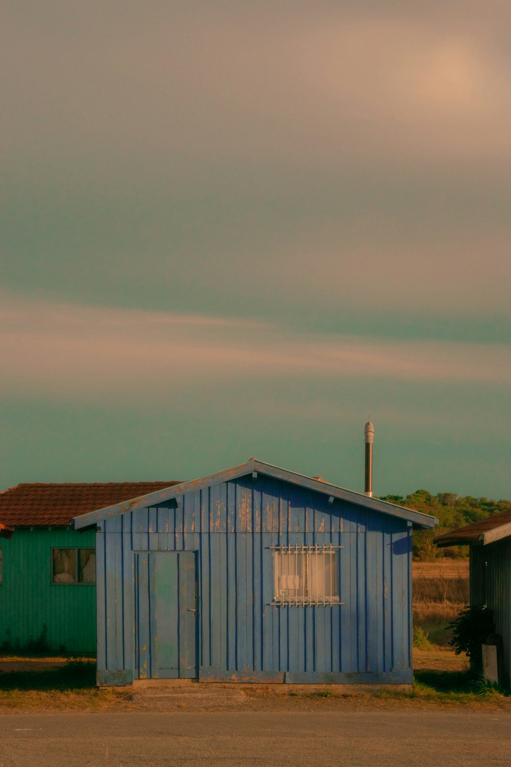 a small blue building sitting on the side of a road