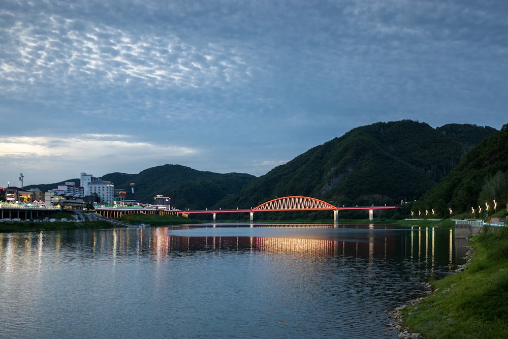 a bridge over a body of water next to a lush green hillside