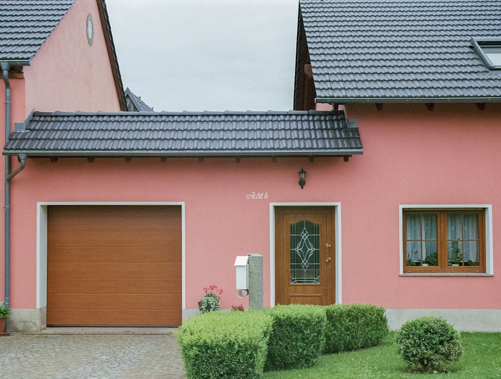 Una casa rosa con una porta marrone e due finestre