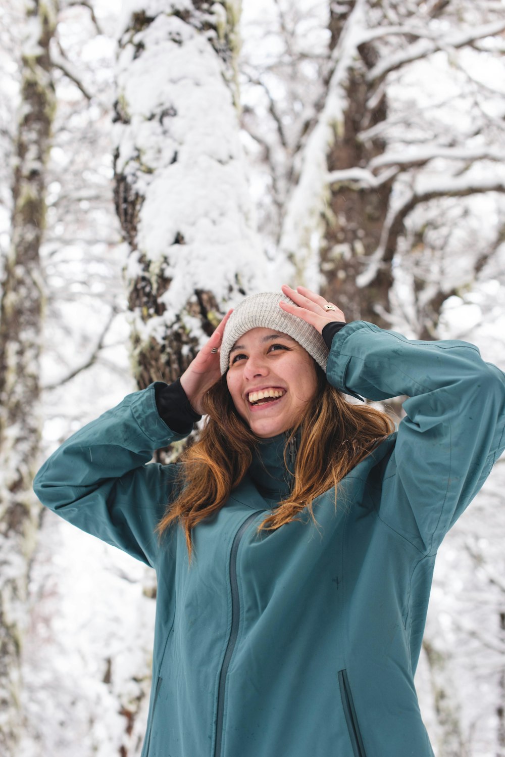 a woman standing in the snow with her hands on her head