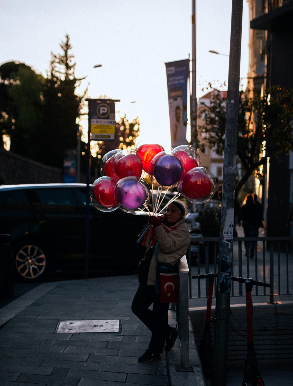a person holding a bunch of balloons on a street