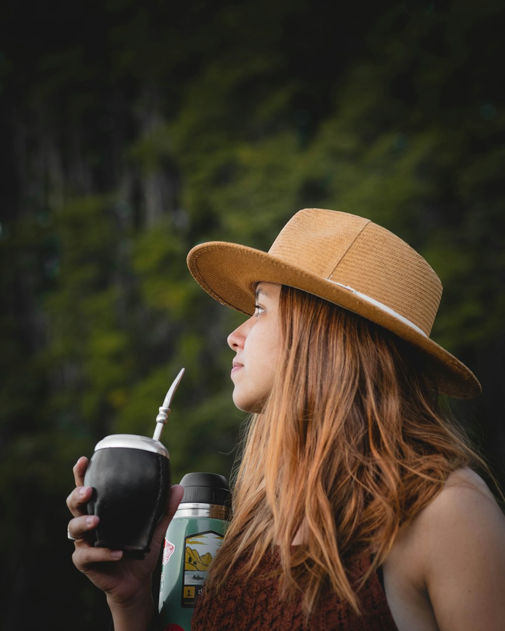 a woman wearing a hat and holding a drink