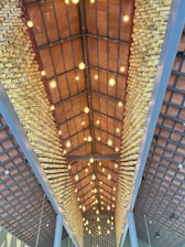 A ceiling structure made from bamboo tubes, arranged geometrically with light bulbs suspended in rows, creating a warm and symmetrical atmosphere. The overall design emphasizes the natural texture of bamboo and provides an intricate, artistic pattern.