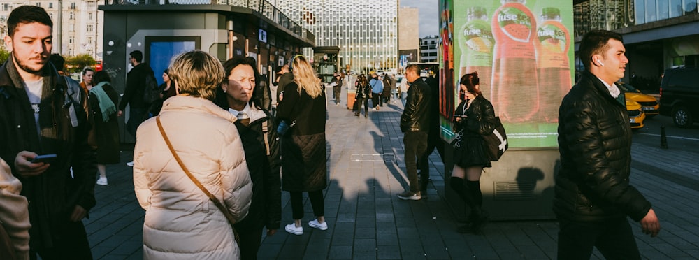 a group of people walking down a street next to tall buildings