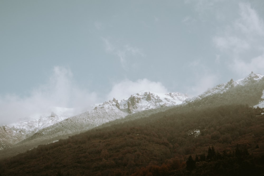 a mountain covered in snow under a cloudy sky