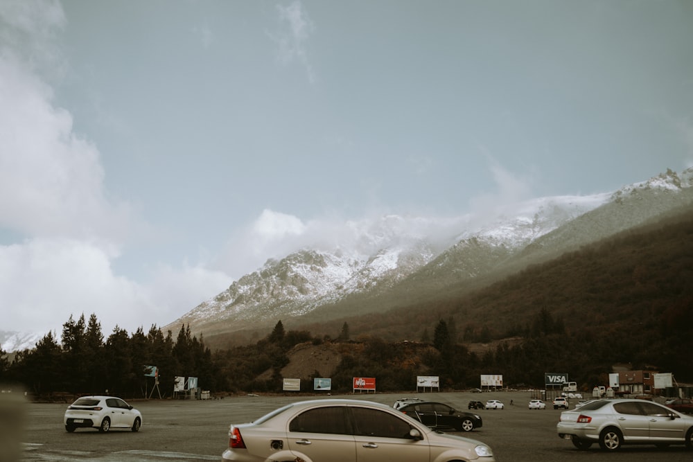 several cars parked in a parking lot with mountains in the background