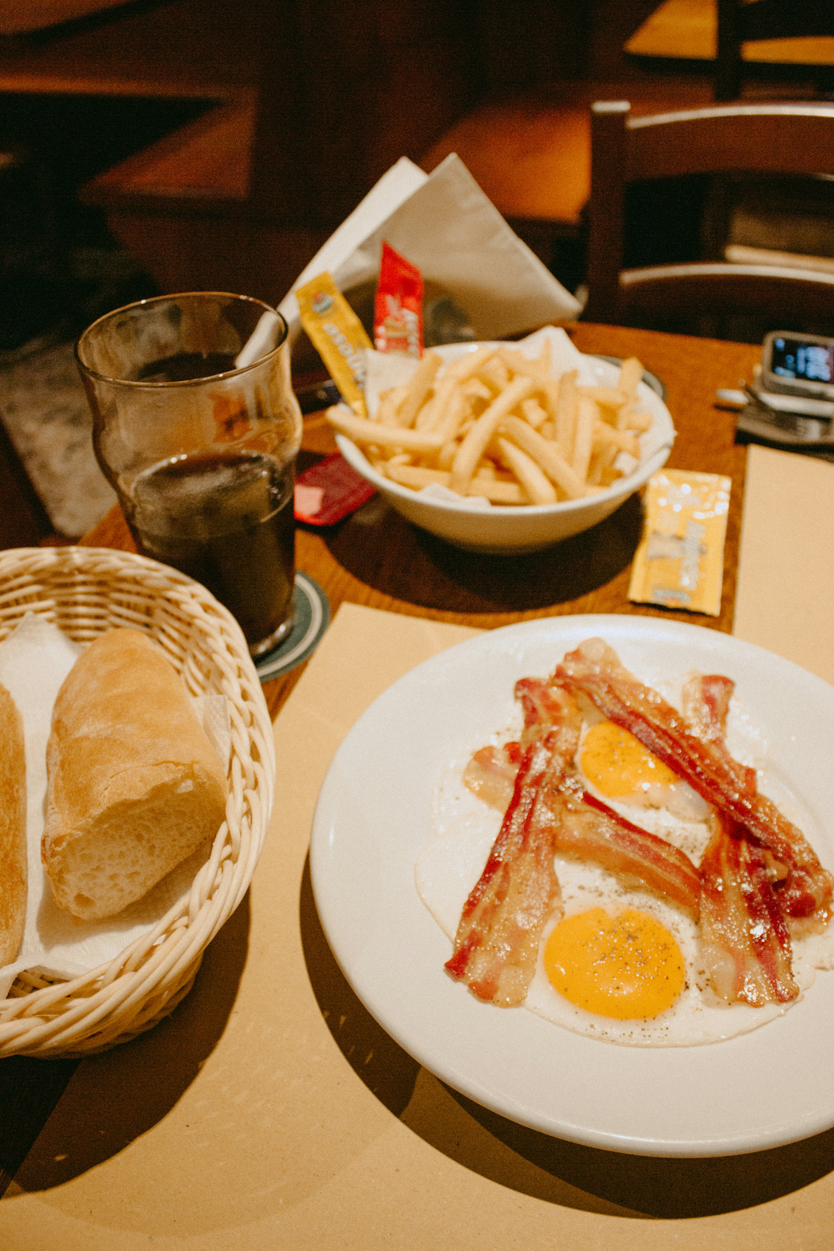 a plate of bacon, eggs and french fries on a table