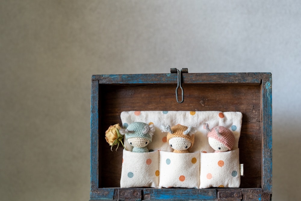 a wooden box with three little stuffed animals in it