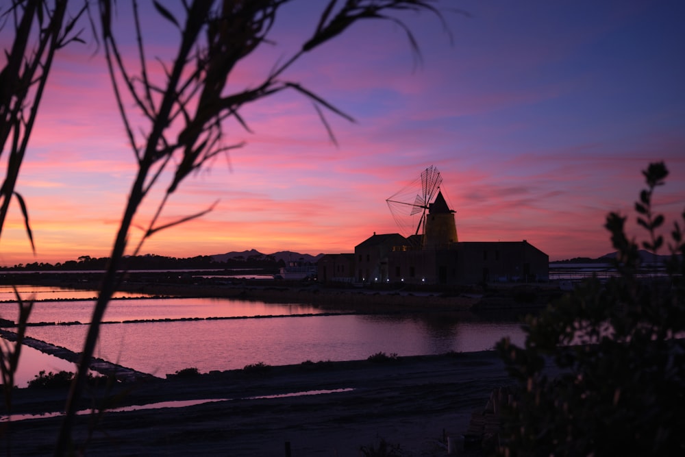 a windmill is silhouetted against a colorful sunset
