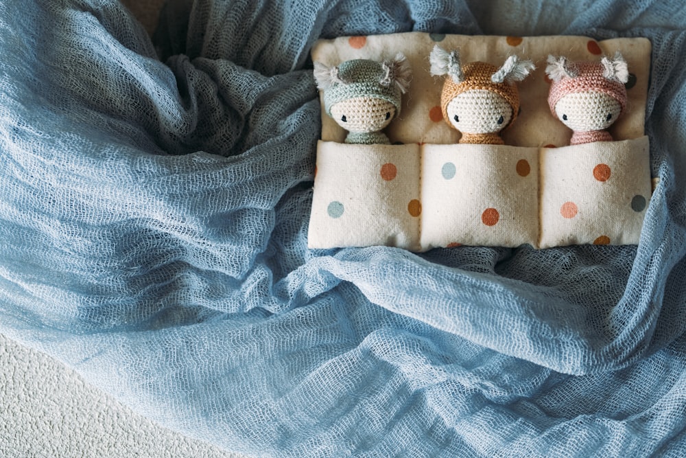 three small stuffed animals sitting on top of a blanket