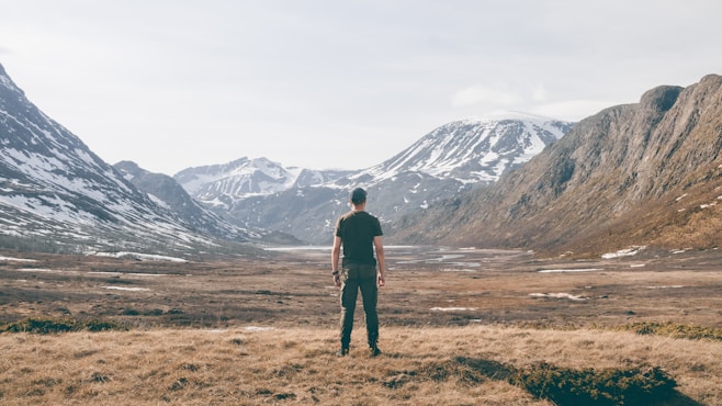 a man standing on top of a dry grass field