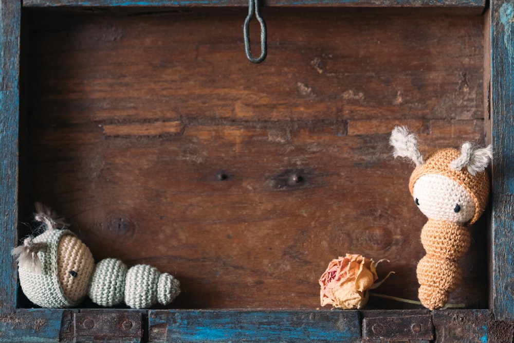 two crocheted animals sitting on top of a wooden shelf