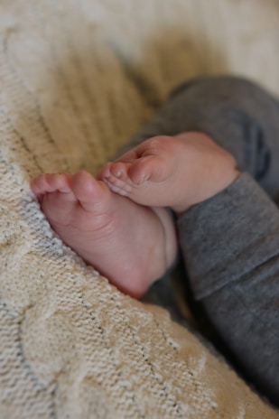 Tiny newborn feet resting gently on a knitted blanket.