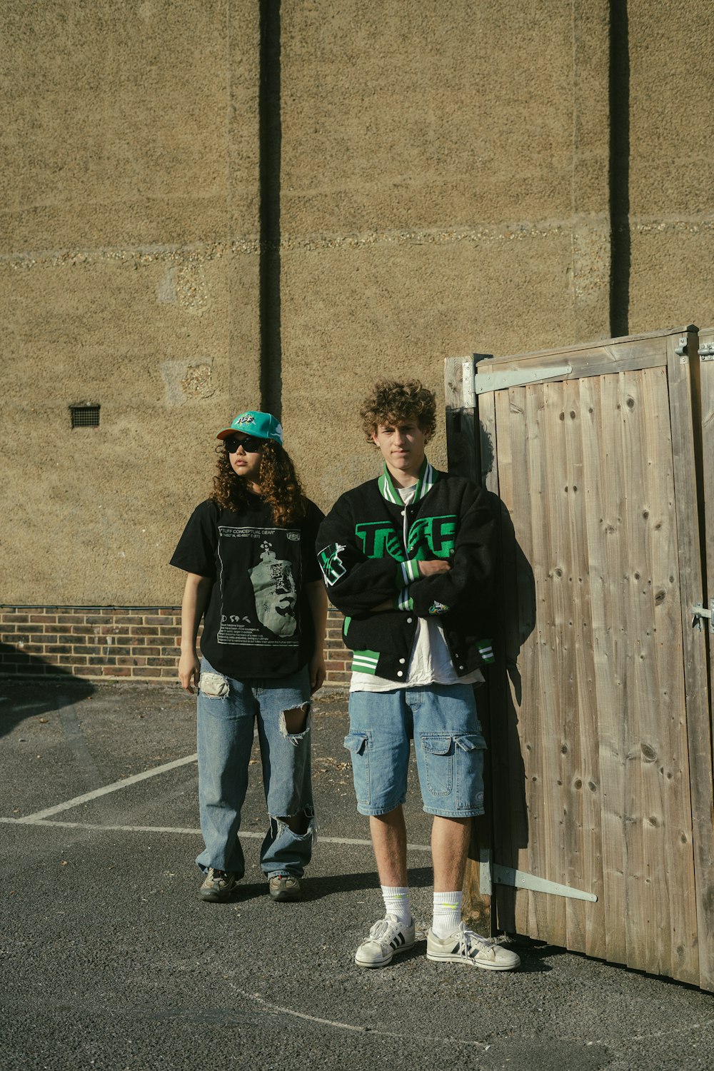 two young men standing next to each other in a parking lot