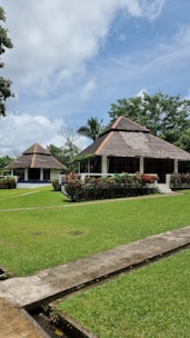 A beautiful 1.5 katha bungalow surrounded by greenery under a clear blue sky.