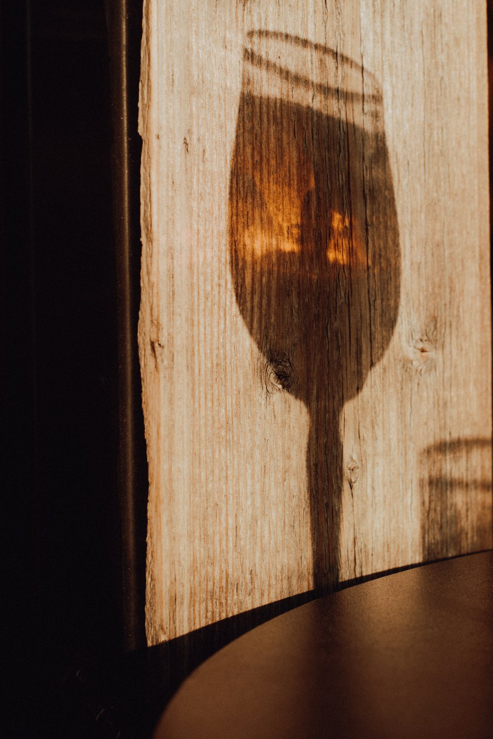 a shadow of a wine glass on a wooden table