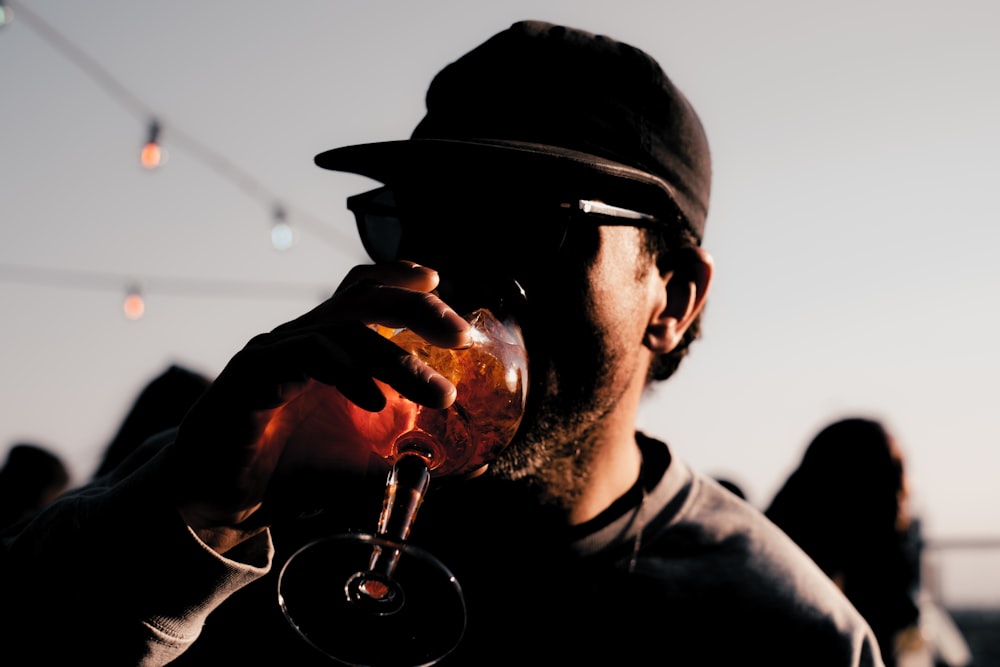 a man in a hat drinking a glass of wine