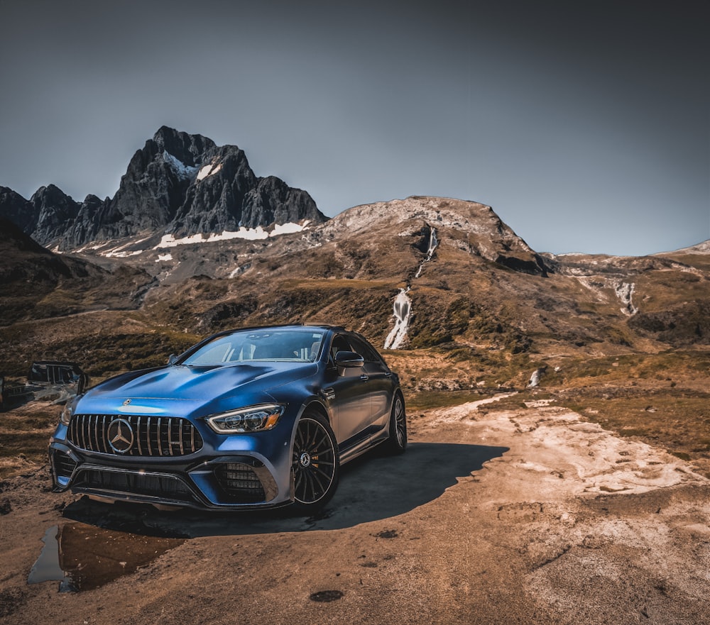 a blue car parked in front of a mountain