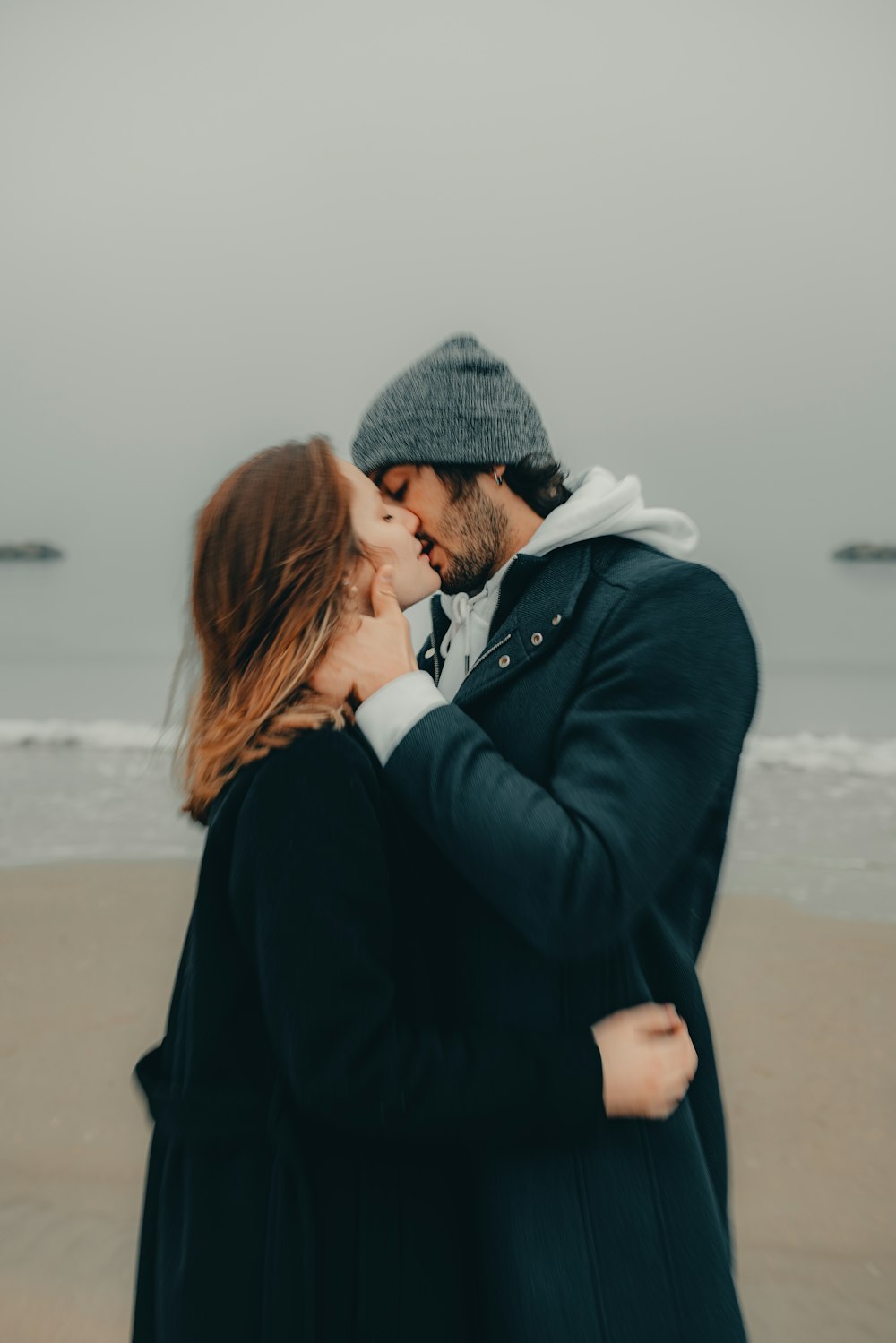 a man and woman kissing on the beach