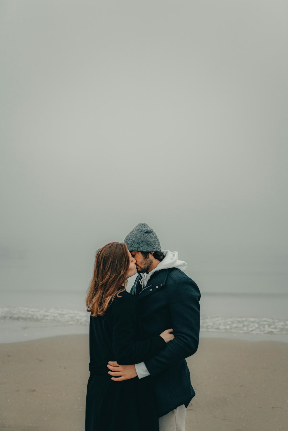 Un couple s’embrassant sur la plage face à l’océan