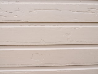 Worker fitting new siding panels on a residential house exterior.