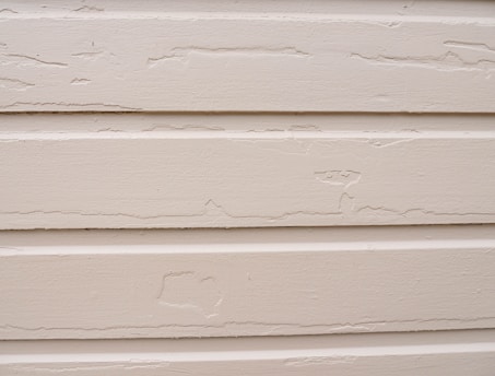 Worker fitting new siding panels on a residential house exterior.