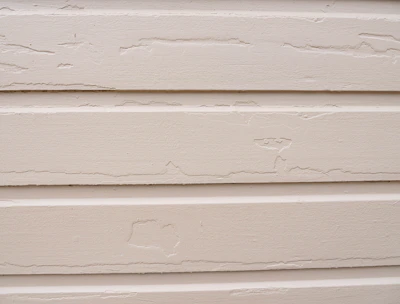 Before and after side-by-side view of a house with repaired siding panels and fresh paint.