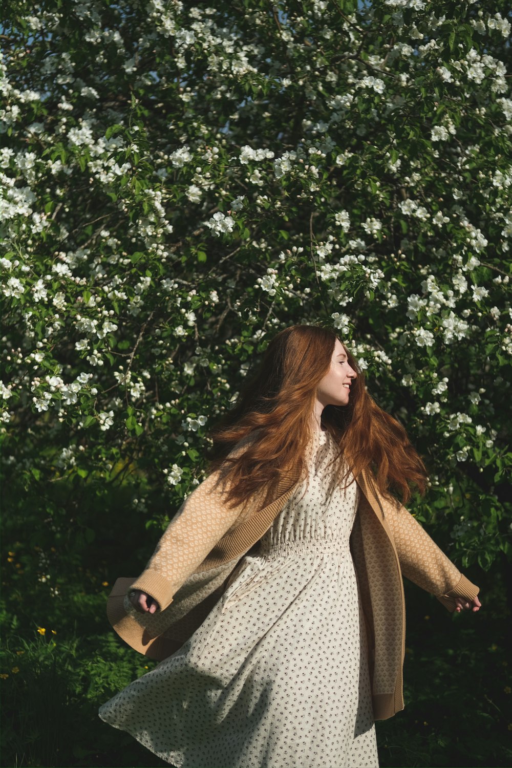 a woman standing in front of a flowering tree