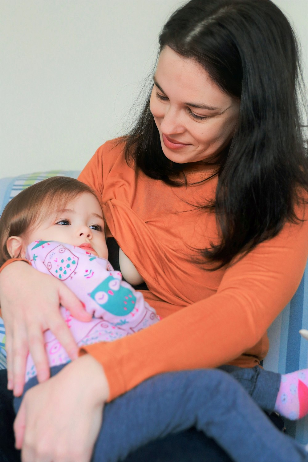 a woman sitting on a couch holding a baby