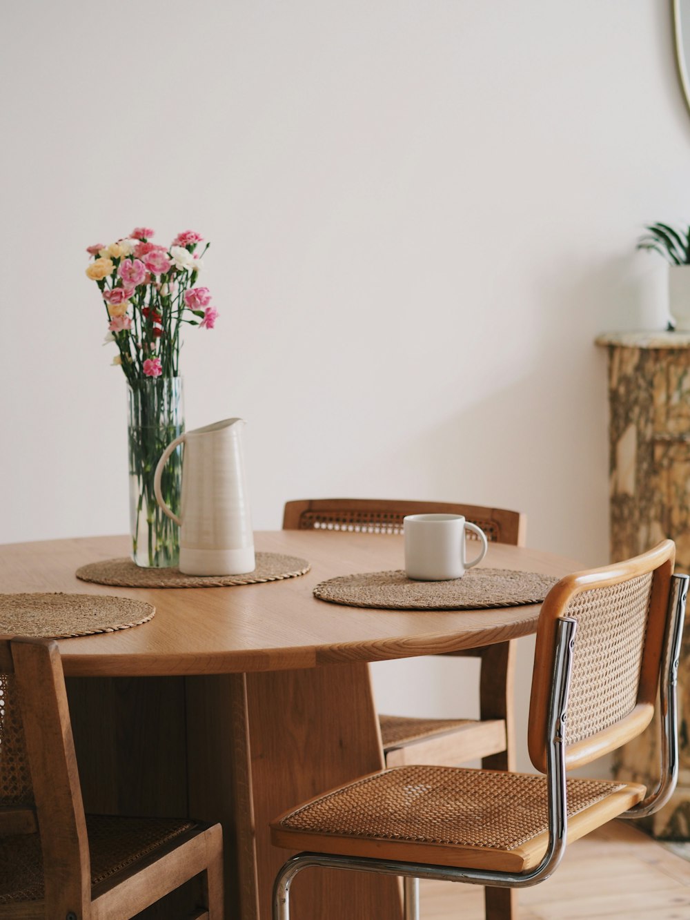 a wooden table with two chairs and a vase of flowers