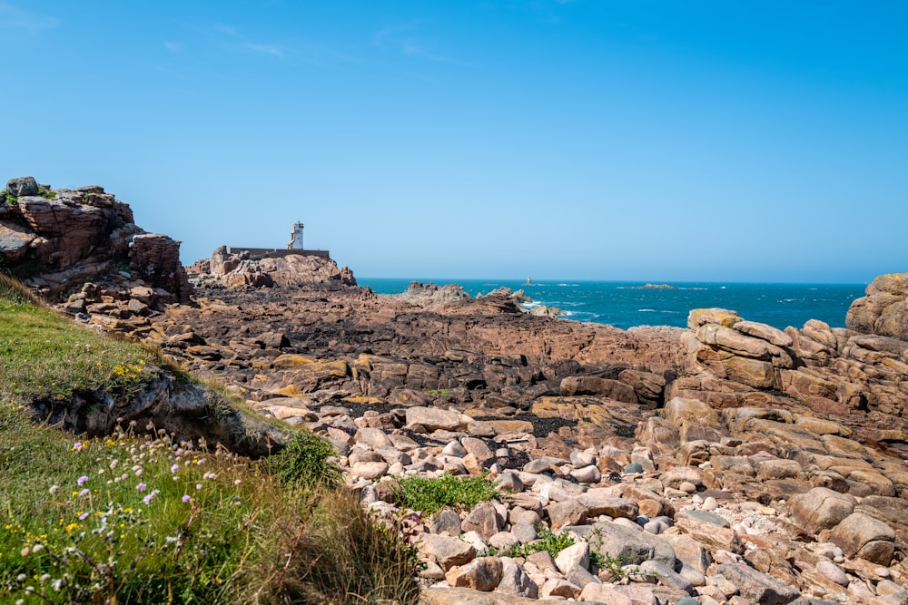 a rocky shore line with a lighthouse in the distance