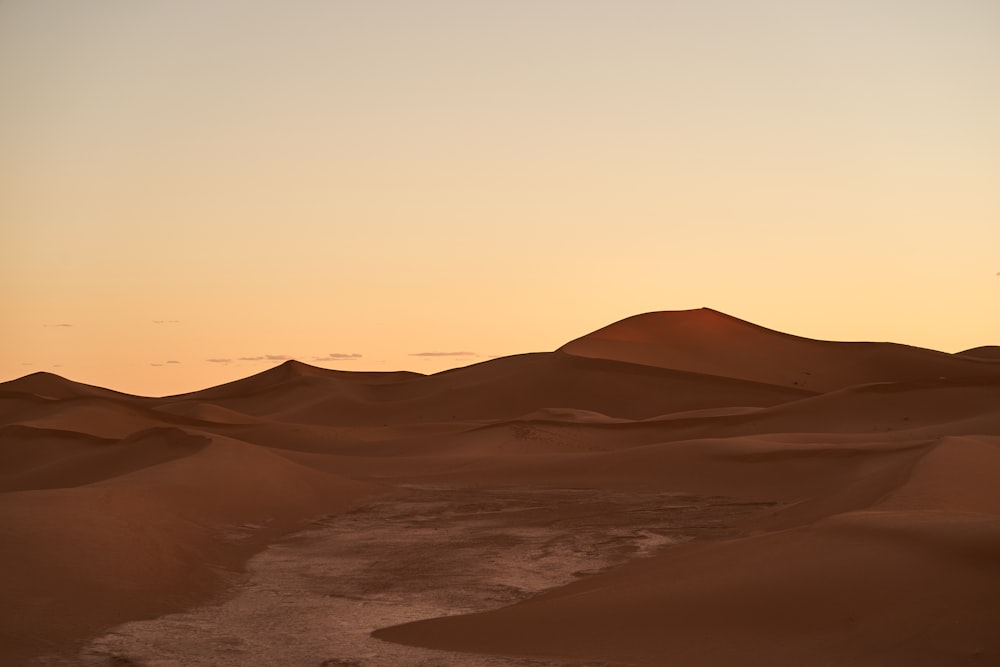 the sun is setting over a desert landscape