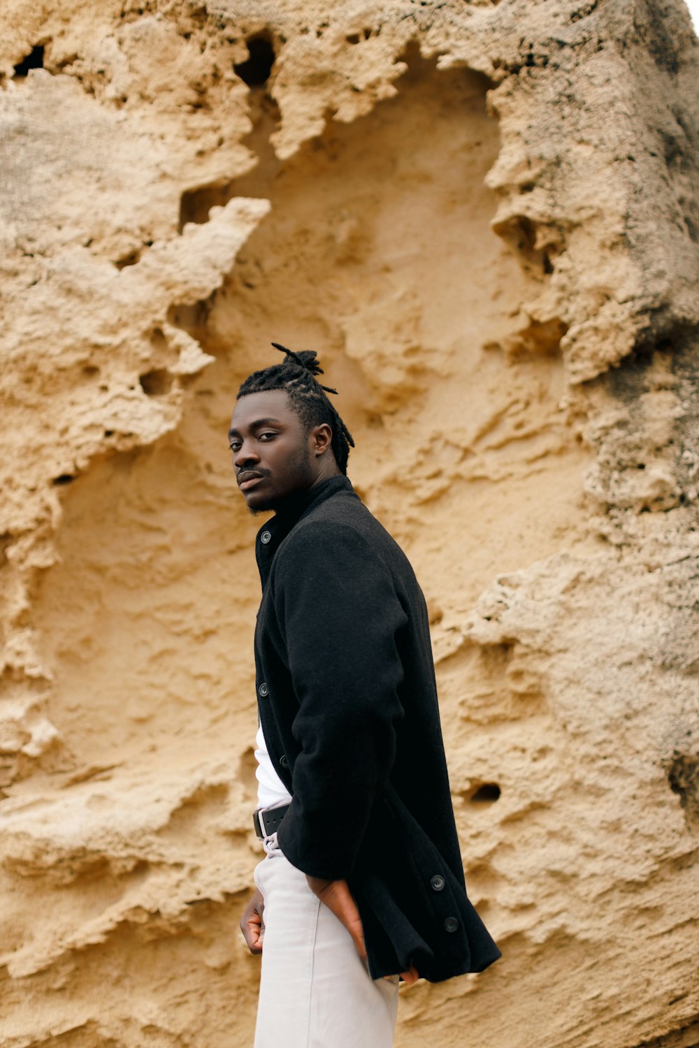 a man standing in front of a rock formation