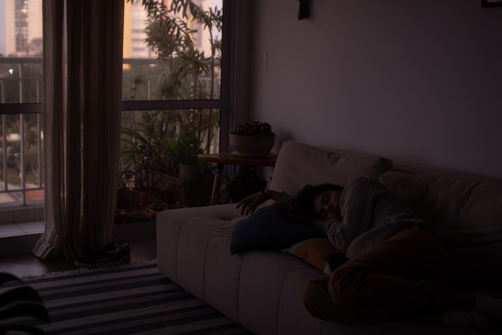 a person laying on a couch in front of a window
