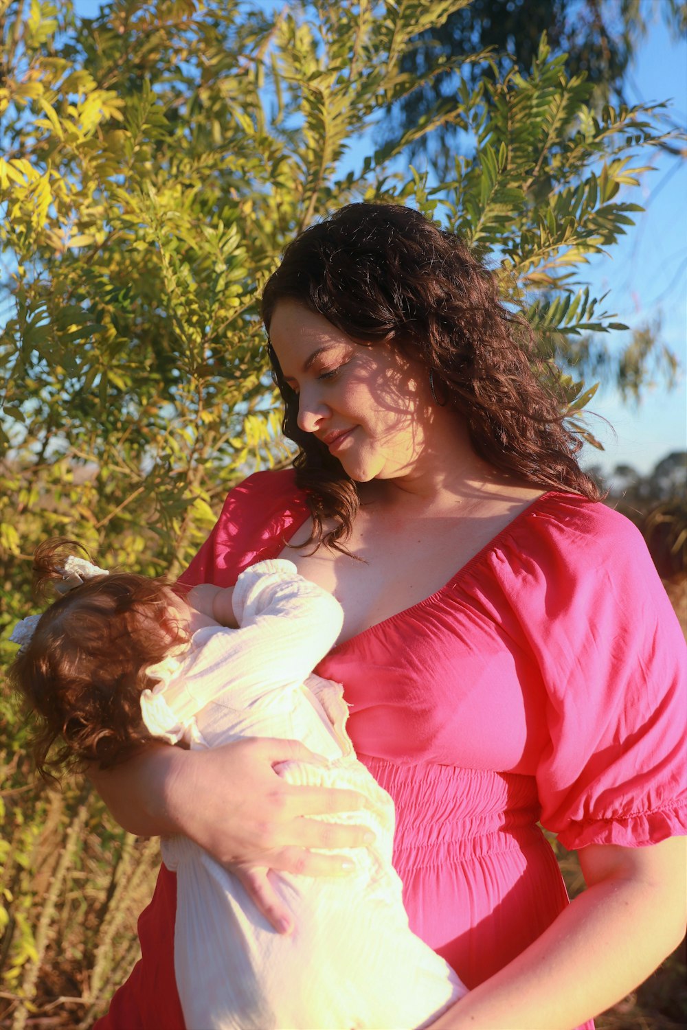 a woman in a pink dress holding a baby