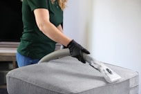 Technicienne de M & M Services Pro nettoyant un pouf gris avec un aspirateur professionnel à Rouen
